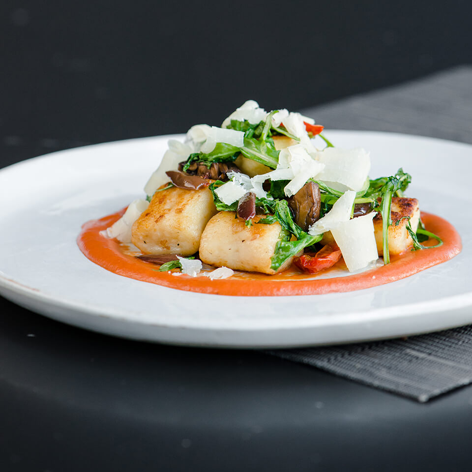 A white plate with ricotta gnocchi in tomato sauce