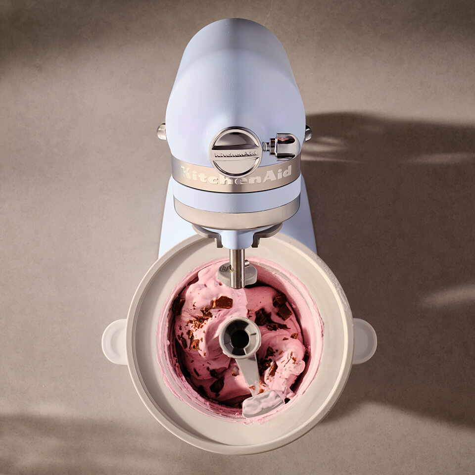An overhead view of a light blue KitchenAid stand mixer mixing ice cream