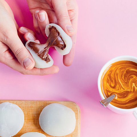 A person breaking a piece of mochi filled with Nutella in half