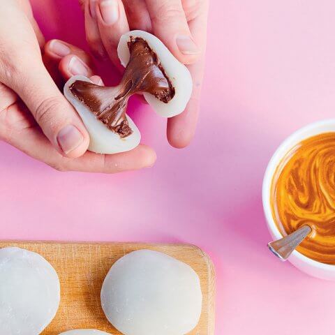 A person breaking a piece of mochi filled with Nutella in half