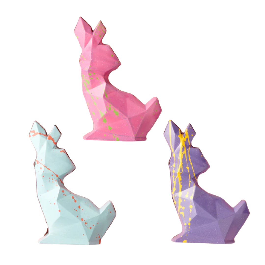 Three polygon-shaped chocolate Easter bunnies; one turquoise, one pink and one purple.