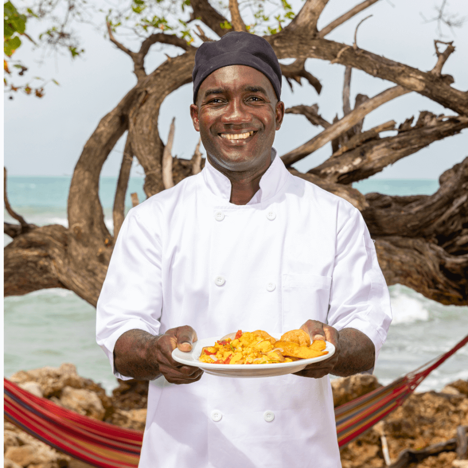 chef holding plate of food on beach