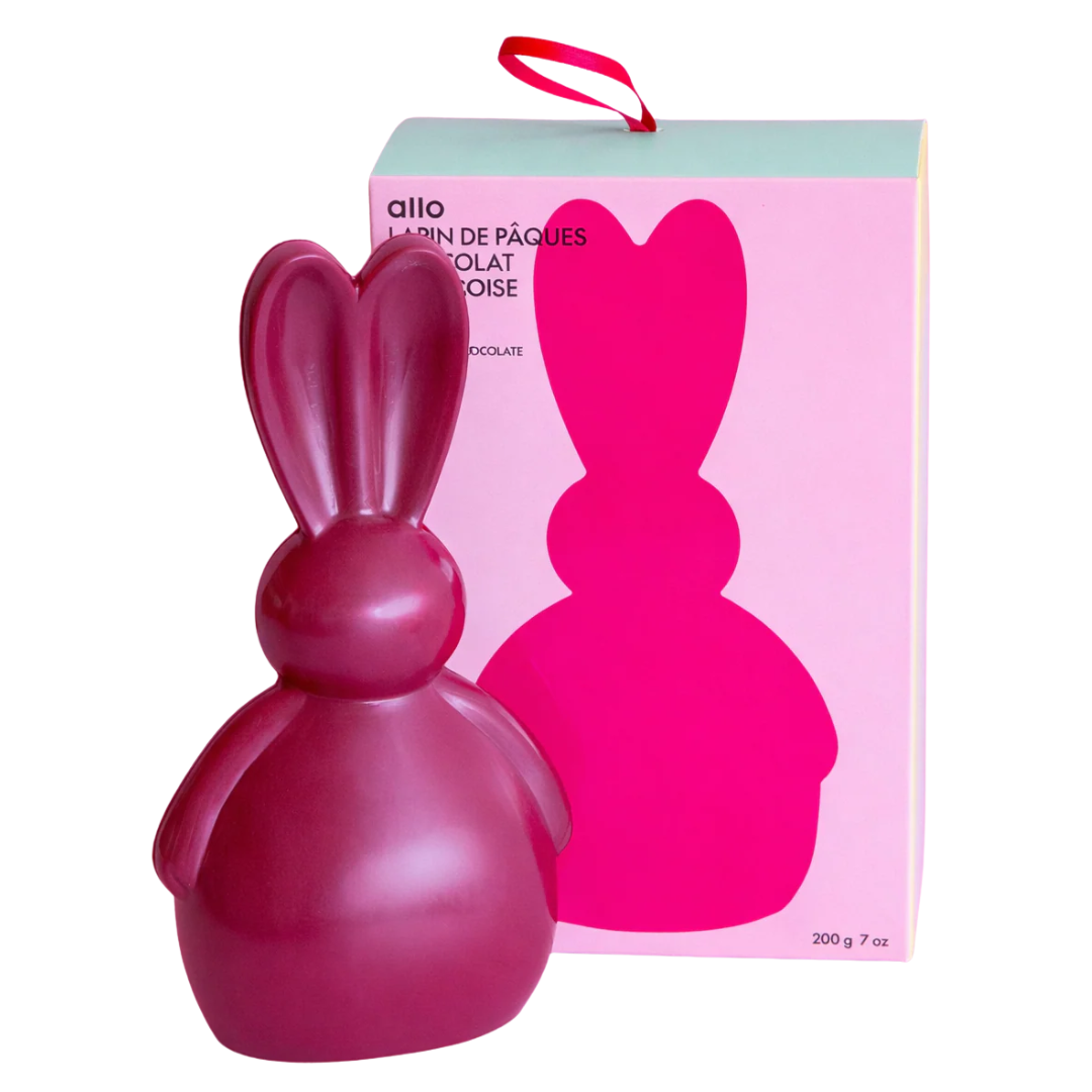 A large pink chocolate Easter bunny in front of a rectangular box packaging. 
