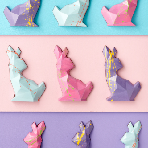 Three rows of three pastel polygon-shaped chocolate Easter bunnies.