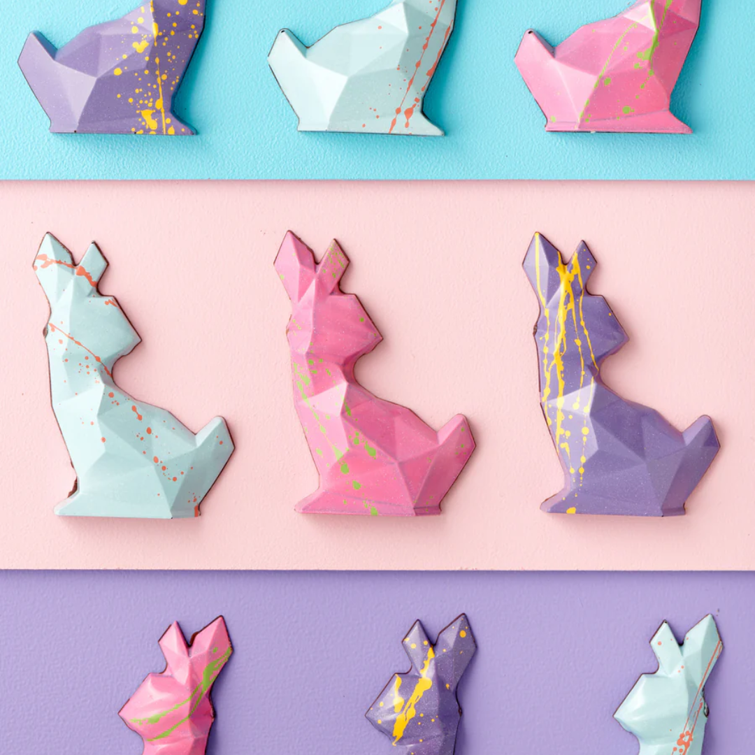 Three rows of three pastel polygon-shaped chocolate Easter bunnies.