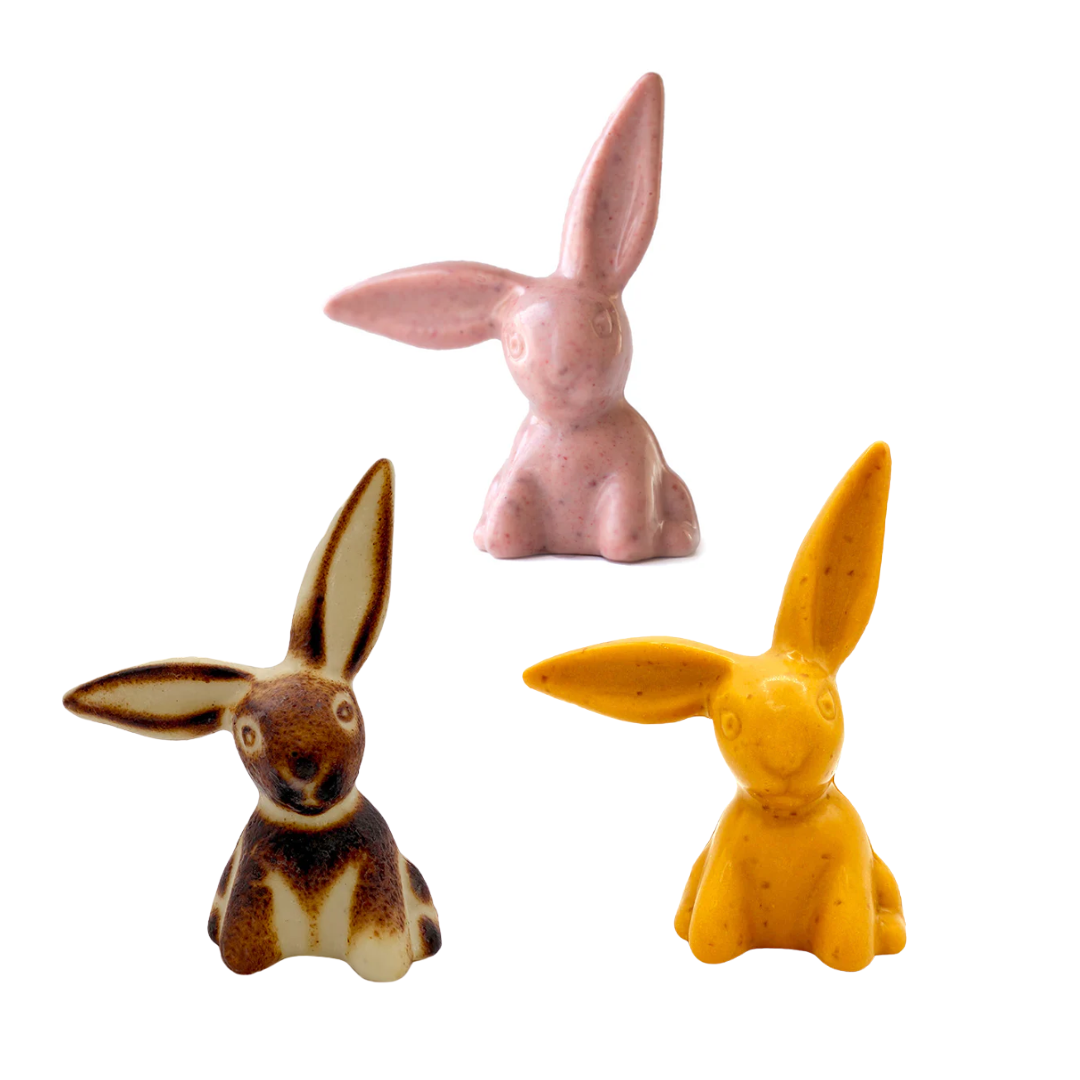 Three chocolate Easter bunnies; one pink, one orange and one toasted white.