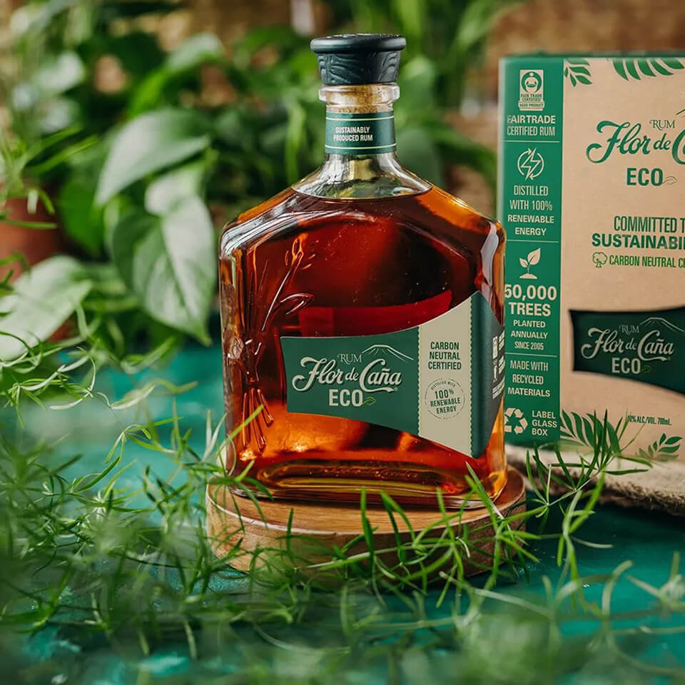 A bottle of rum on a wooden circle on a green surface with plants around it