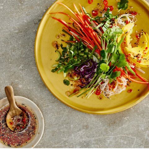 Colourful salad with julienned vegetables and ginger sesame dressing in a small dish