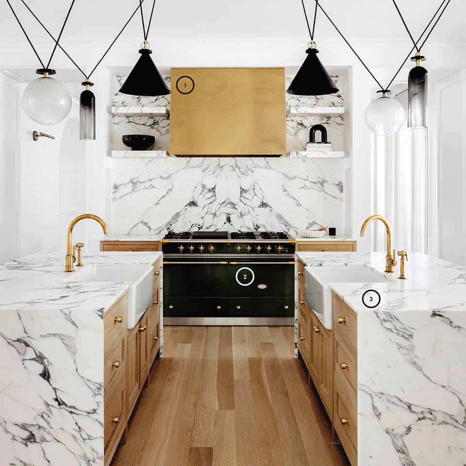 A view of a kitchen in white marble and wood tones, with small numbers over it