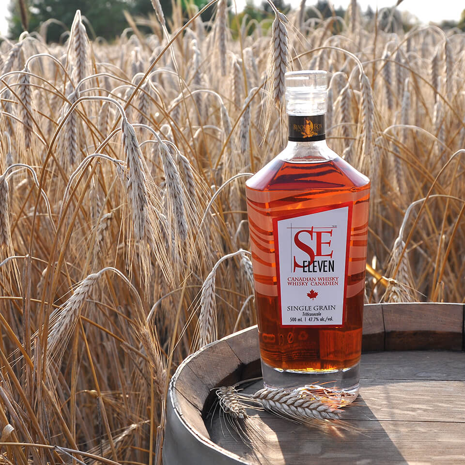 A bottle of whisky on a barrel in a wheat field