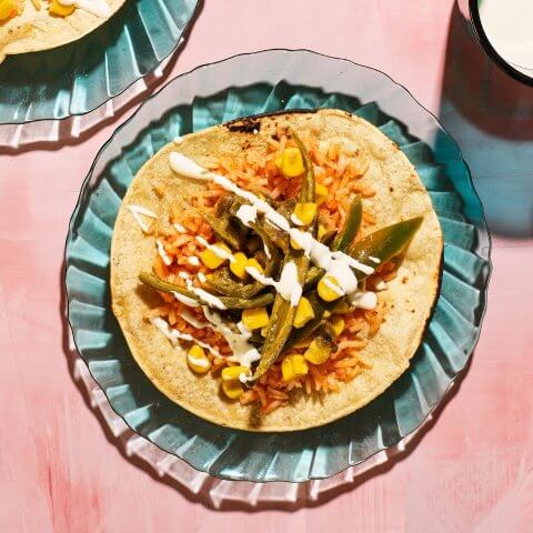 A blue dish with a taco on a pink surface