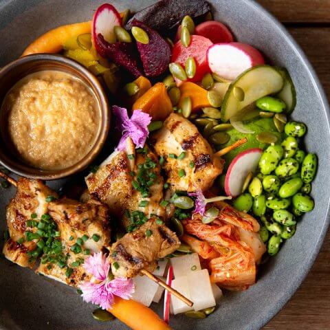 A bowl filled with various healthy fillings and a small dish of sauce