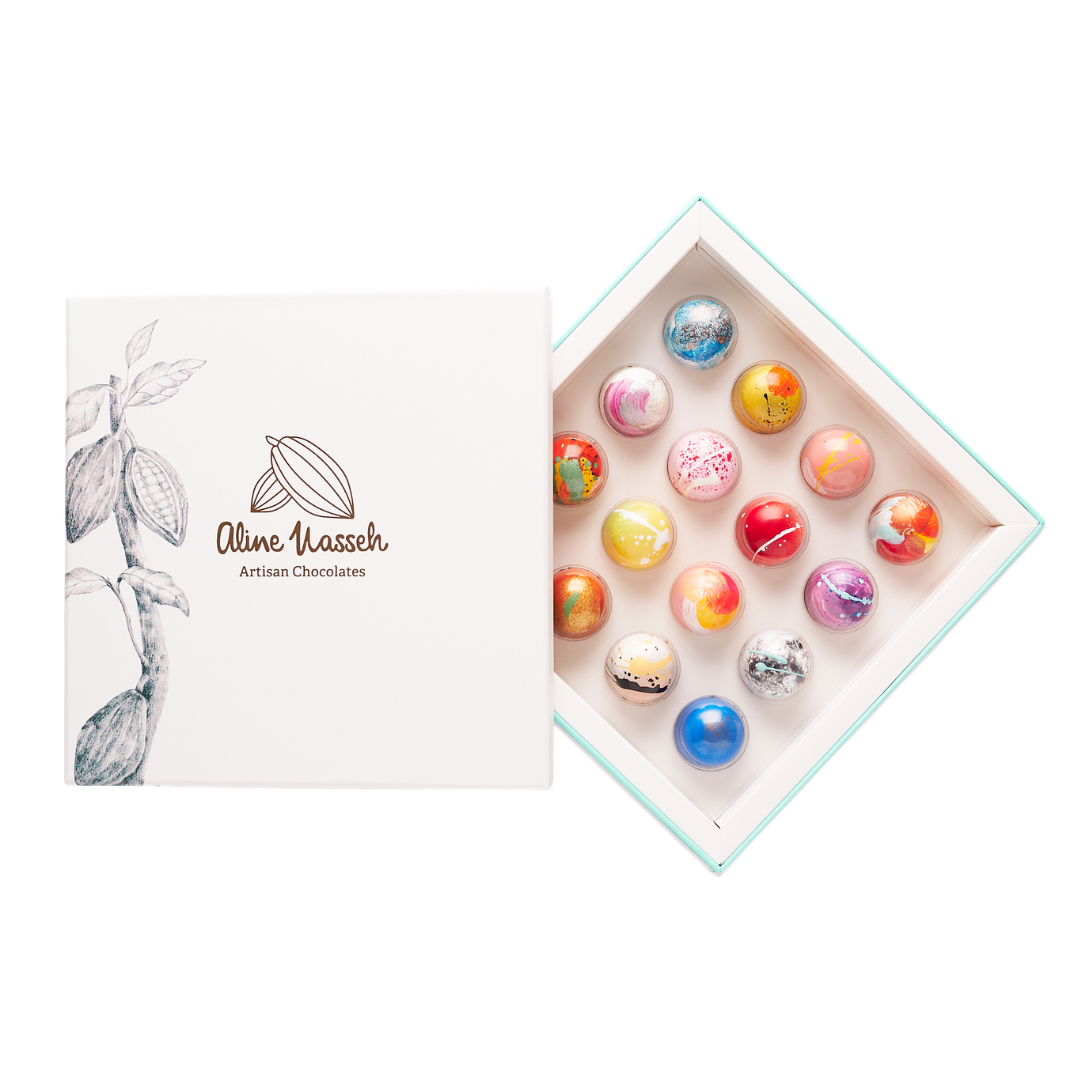 A white box opened to show 16 colourful chocolate truffles. 