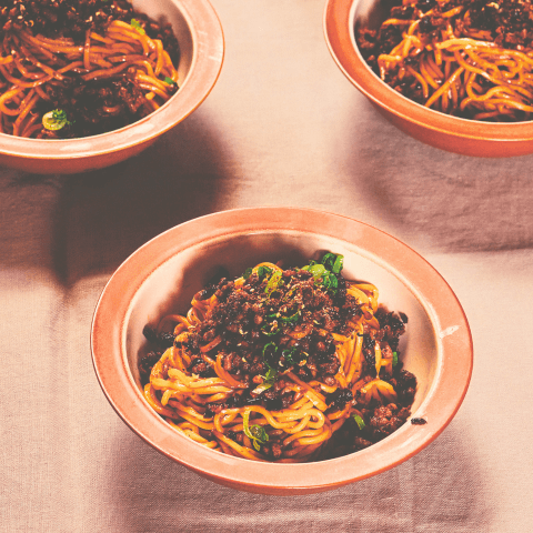 Three bowls of noodles in pink bowls
