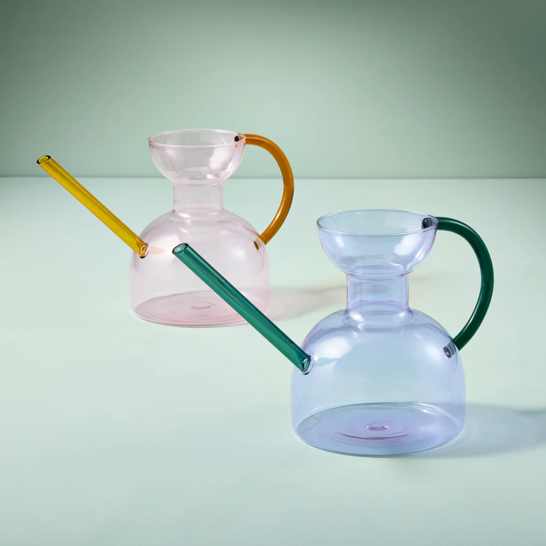 A pink glass watering can and a blue glass watering can.
