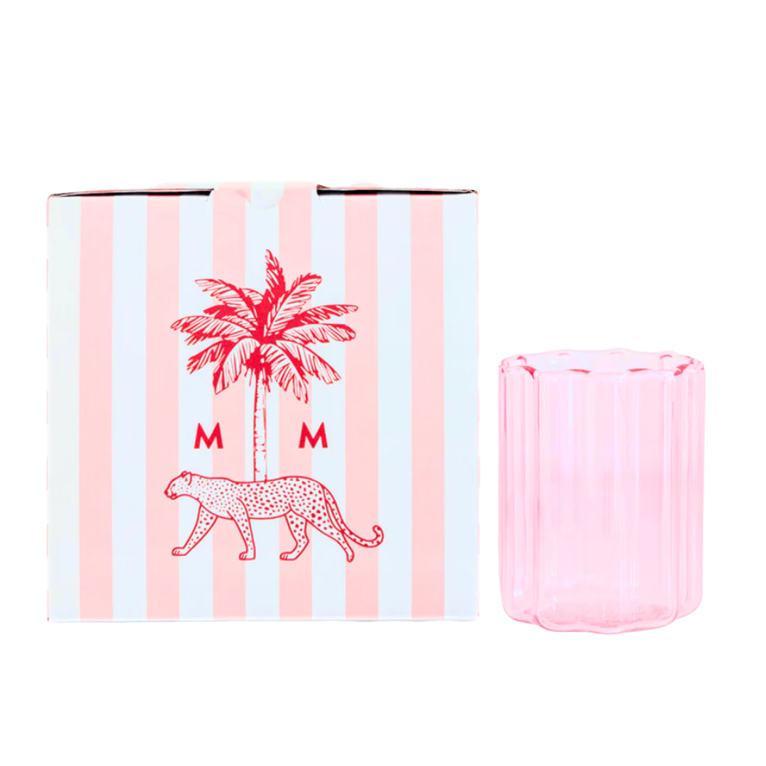 Pink flower-shaped glass next to a striped box. 