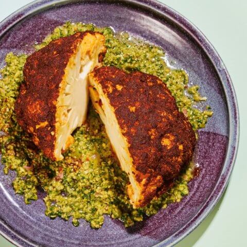 Roasted cauliflower with green dressing on a purple plate