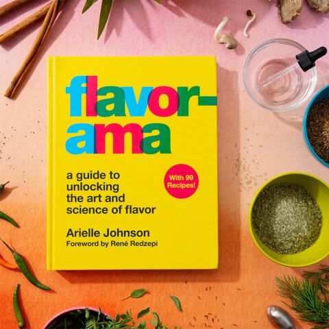 A book on a pink surface surrounded by vials and other scientific equipment