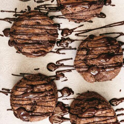 Chocolate scones on parchment paper drizzled with chocolate