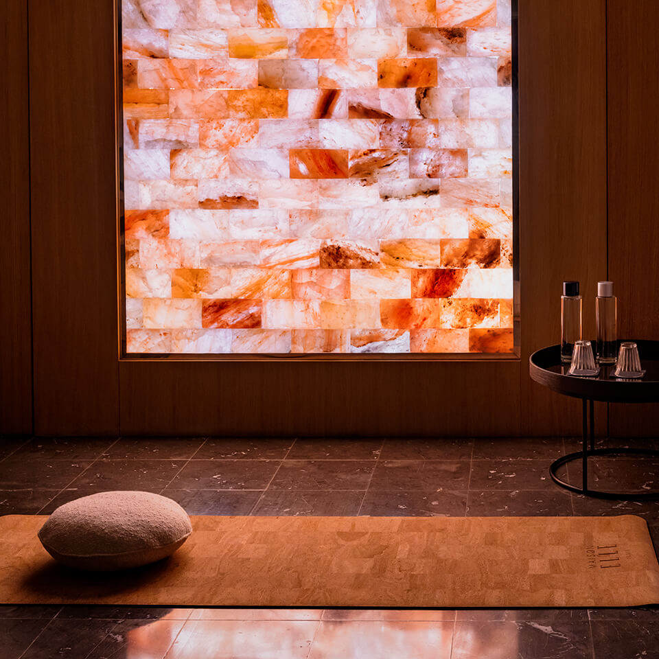 A yoga mat and pillow with a salt brick panel visible behind them