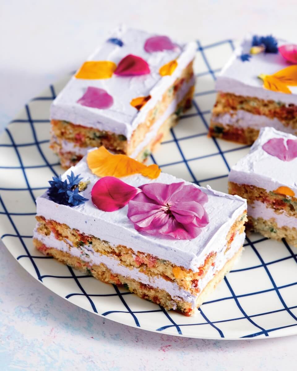 Vegan floral Dessert bars with pressed flowers in the frosting on a plate with a grid pattern