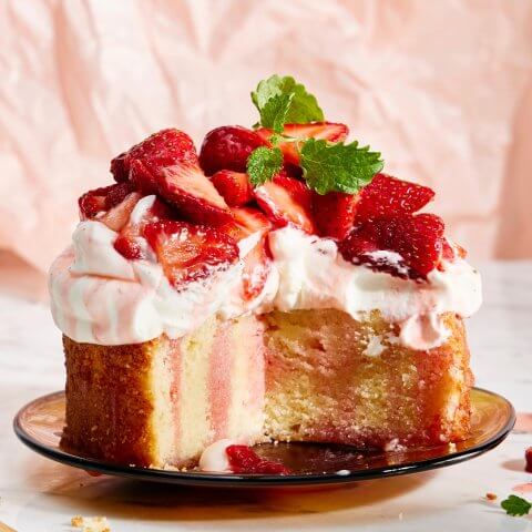 A cake topped with frosting and sliced strawberries on a plate