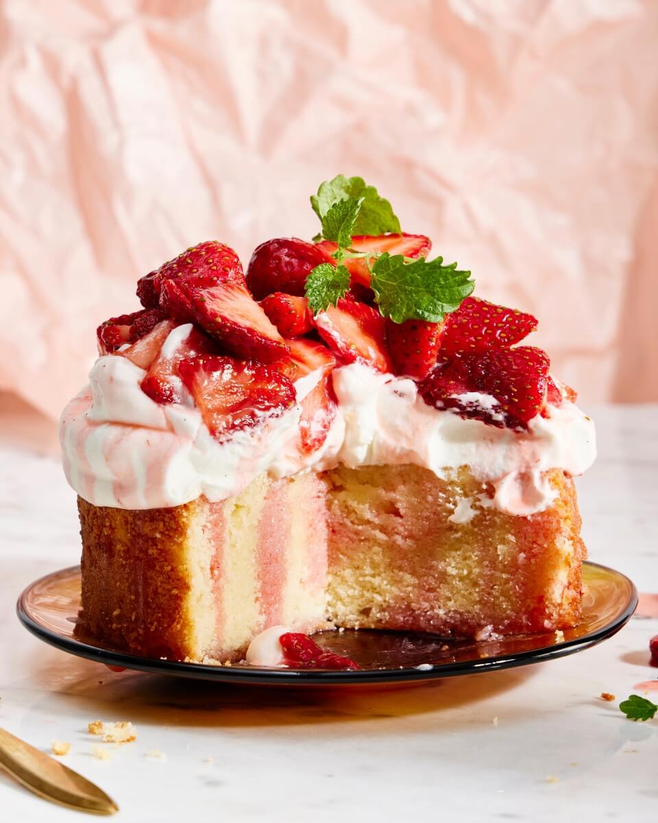 A cake topped with frosting and sliced strawberries on a plate