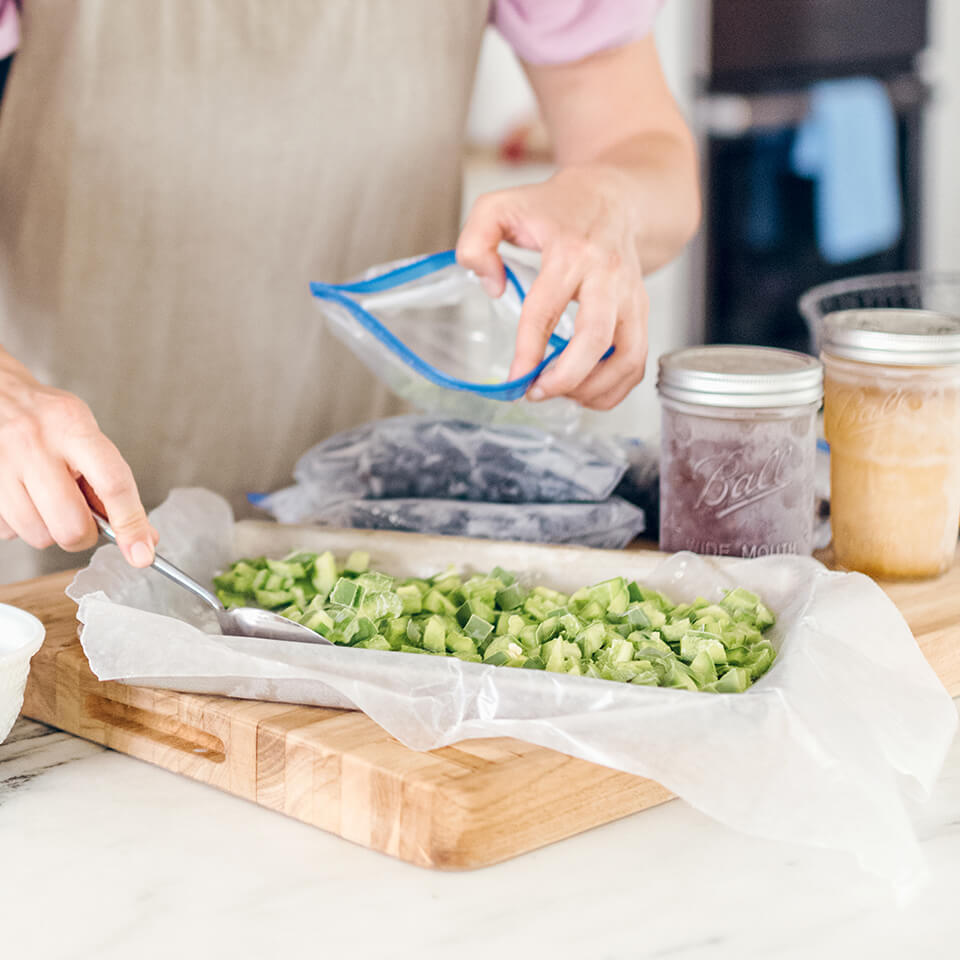 A person's hands spooning chopped bell pepper onto wax paper