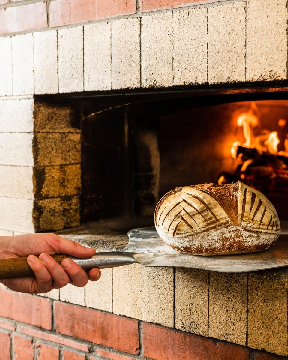 A person taking bread out of an oven