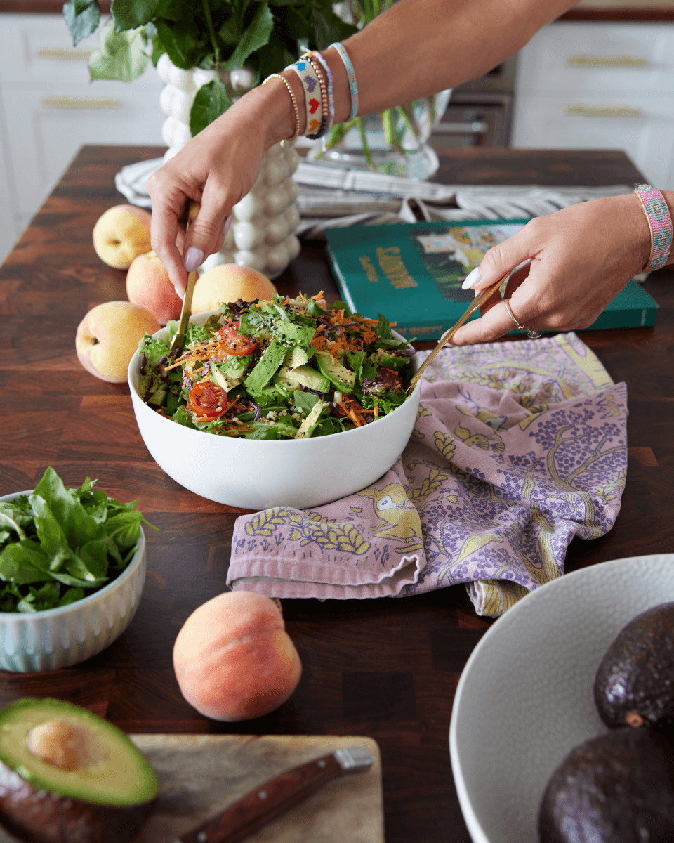 person's hands tossing a green salad