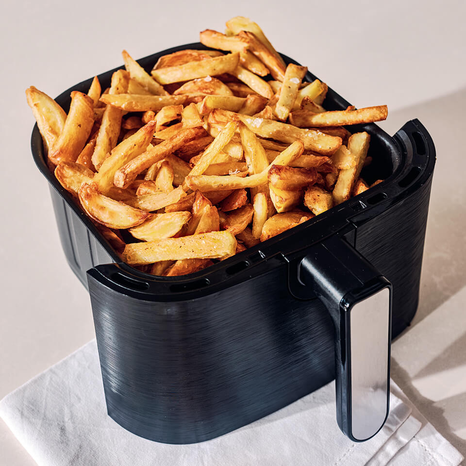An air fryer basket with french fries