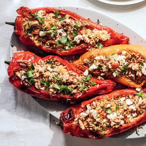 Air fryer vegetarian stuffed peppers with walnuts and fresh parsley on a serving platter.