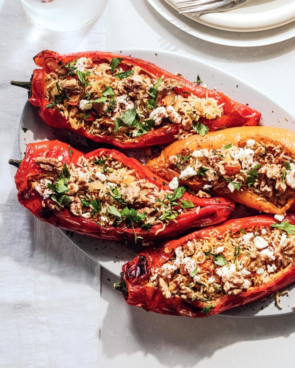 Air fryer vegetarian stuffed peppers with walnuts and fresh parsley on a serving platter.