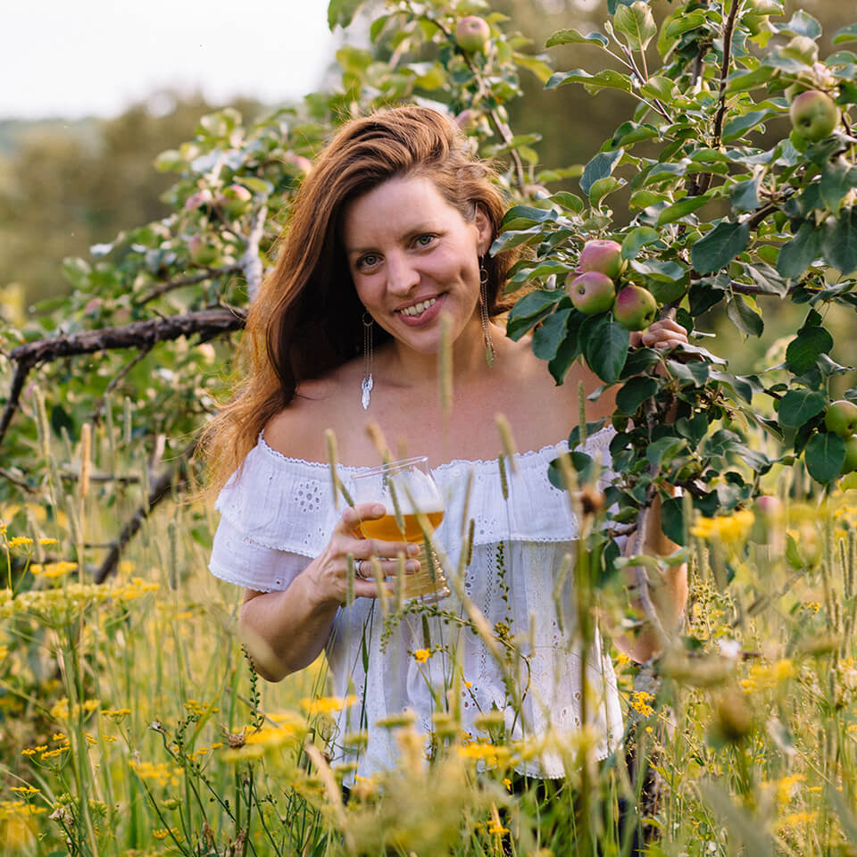 Canadian pommelier Jeannie Dubois holds a glass of Ontarion cider in an apple field