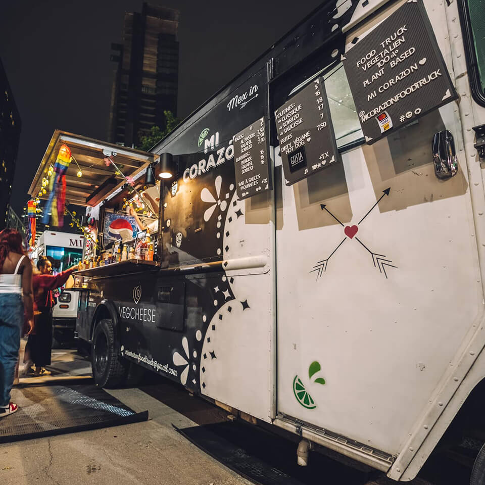 People lining up at a black-and-white food truck during nighttime