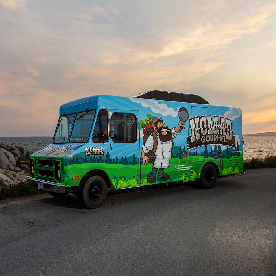 A food truck on a road in front of the ocean at dusk