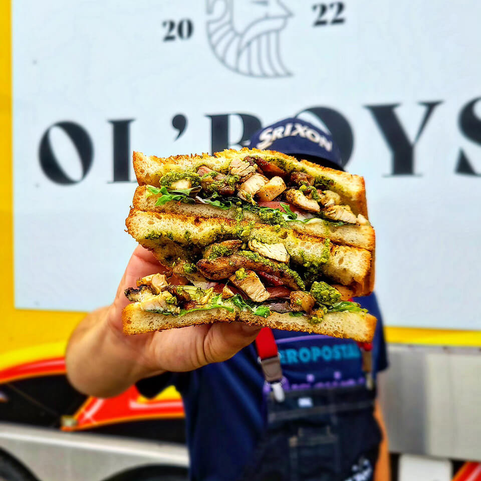 A person holding up a sandwich in front of a food truck