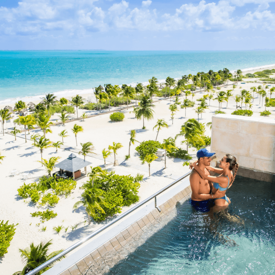Man and woman in plunge pool with caribbean beach background