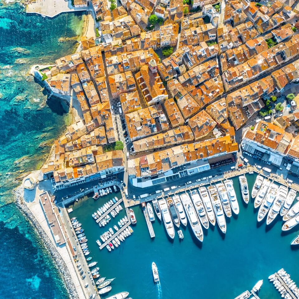 An overhead drone shot of Saint Tropez with many boats in the harbour