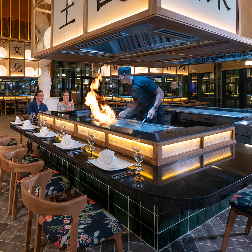 Two people watching a chef at a Japanese restaurant