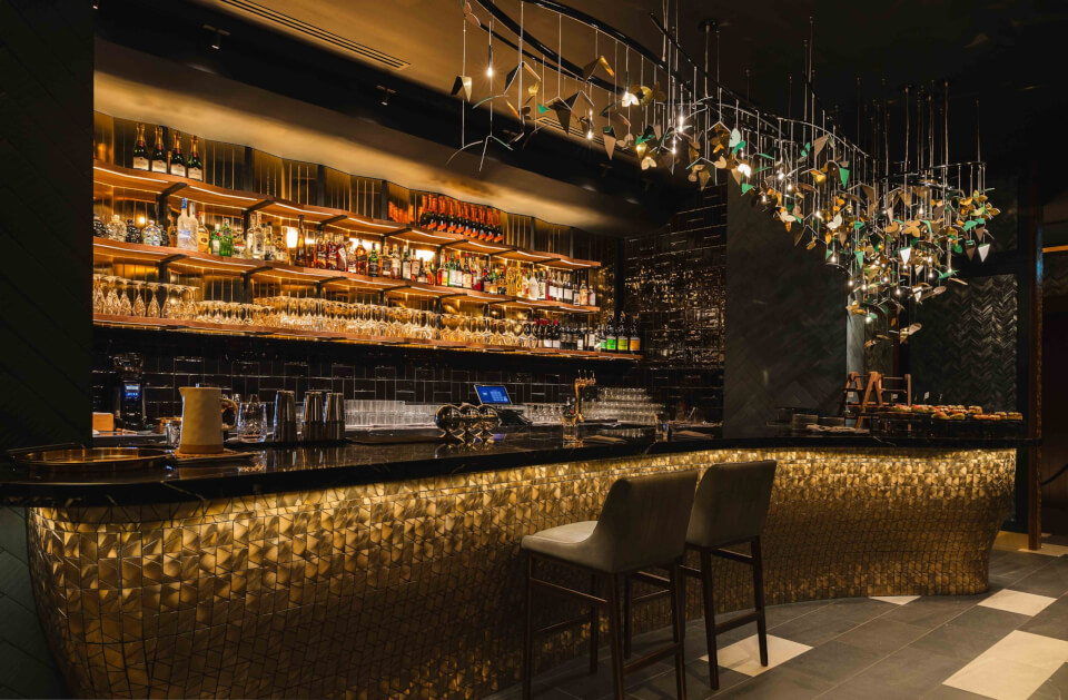 Cocktail bar with moody lighting and rows of bottles of alcohol