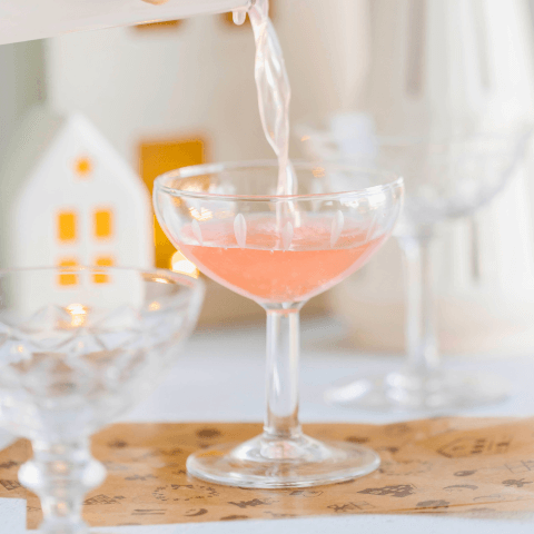 pink cocktail next to bottles