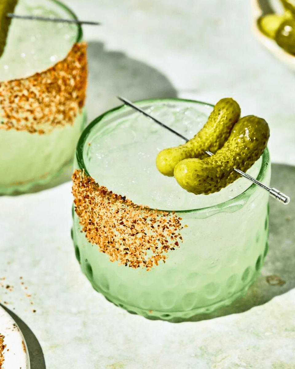 glass with pickles on cocktail skewer