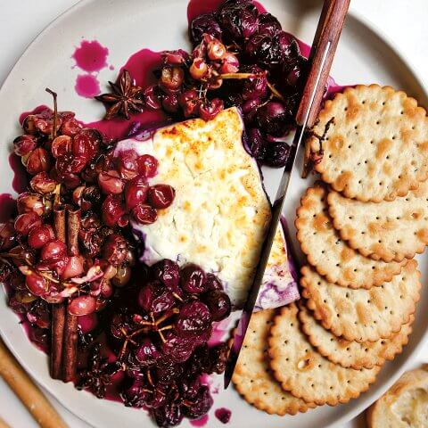 A dish with cheese, grapes and crackers