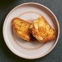 A pink plate with an almond cookie broken in half Cantucci Italian almond biscotti broken in half on a plate