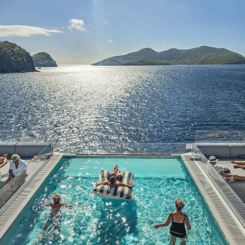 people enjoying themselves in a pool on a cruise ship looking at caribbean view