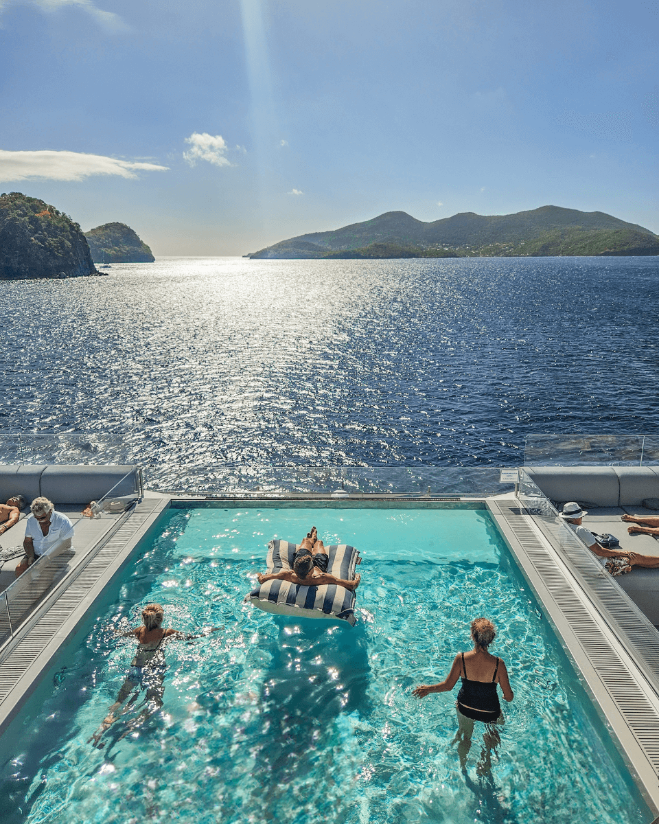 people enjoying themselves in a pool on a cruise ship looking at caribbean view