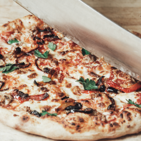 Knife cutting into freshly cooked frozen pizza from a Canadian Company