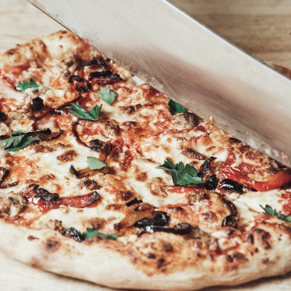 Knife cutting into freshly cooked frozen pizza from a Canadian Company