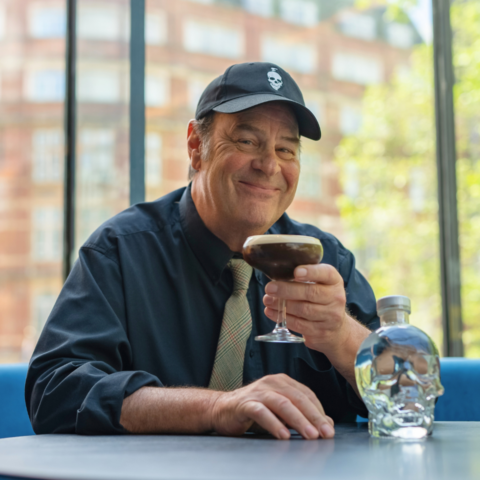 Portrait of Canadian actor Dan Aykroyd holding an espresso martini made with Skull Vodka